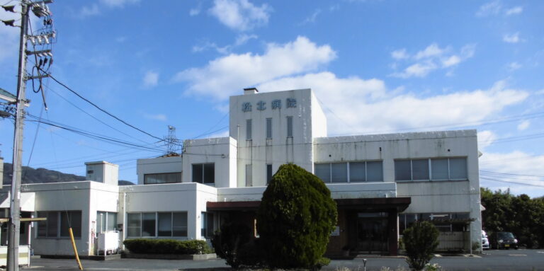 介護施設の白い建物外観。複数階建てで看板が見える